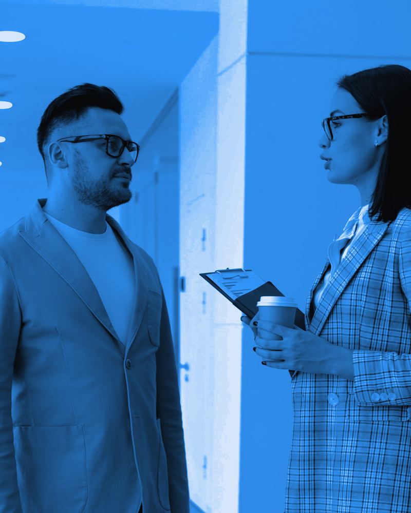 Colleagues in business attire talking in a modern office hallway