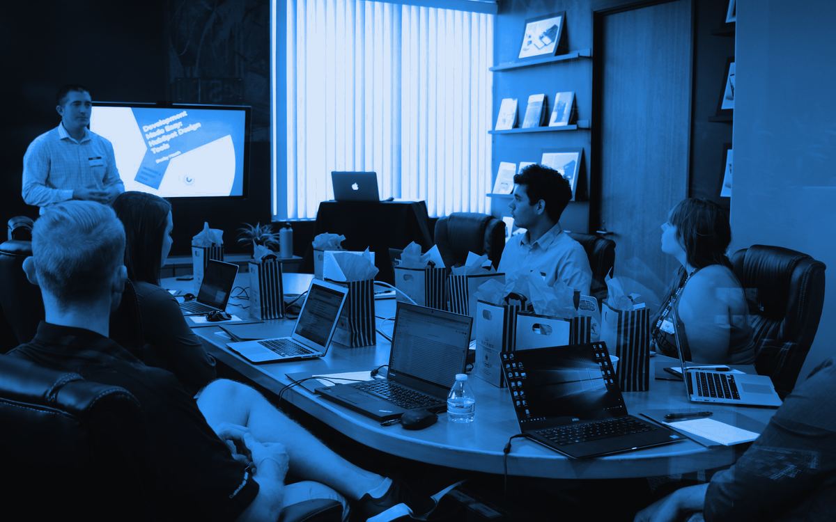 A leader presenting to a team seated around a conference table