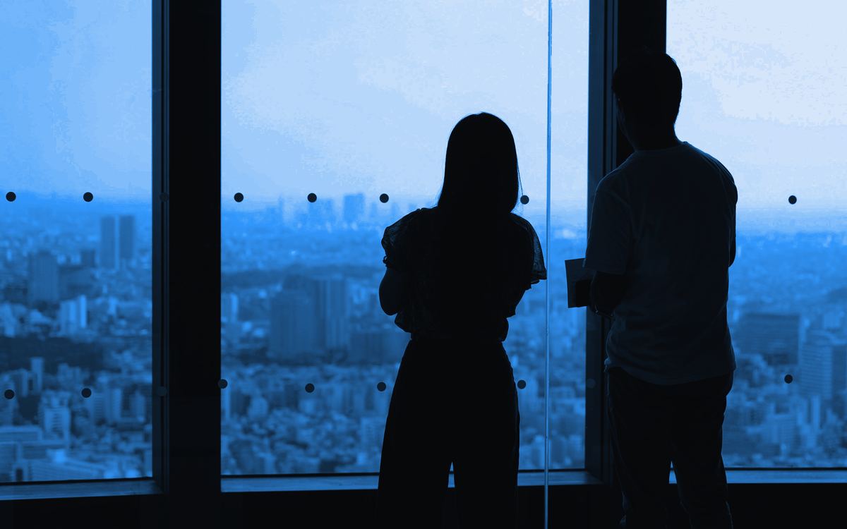 Two professionals looking out an office window over the city skyline