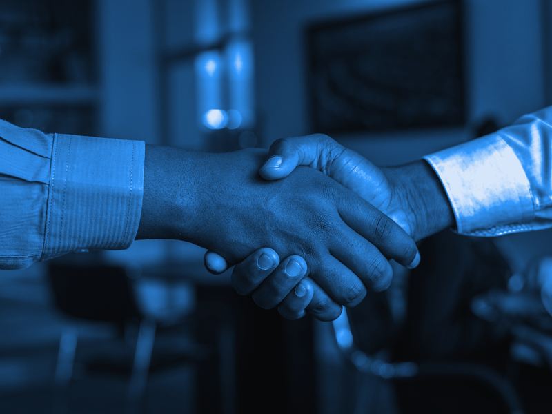 Two professionals shaking hands across a table