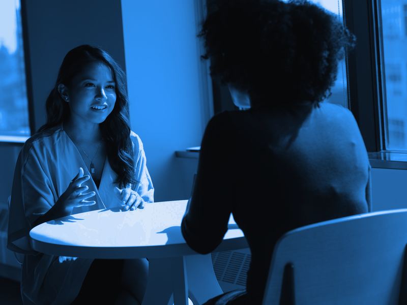 A mentor coaching a young professional in a bright office